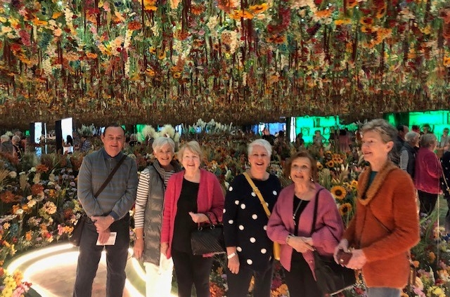 Samford Grove residents smiling under a sea of flowers at Monet in Paris exhibit.