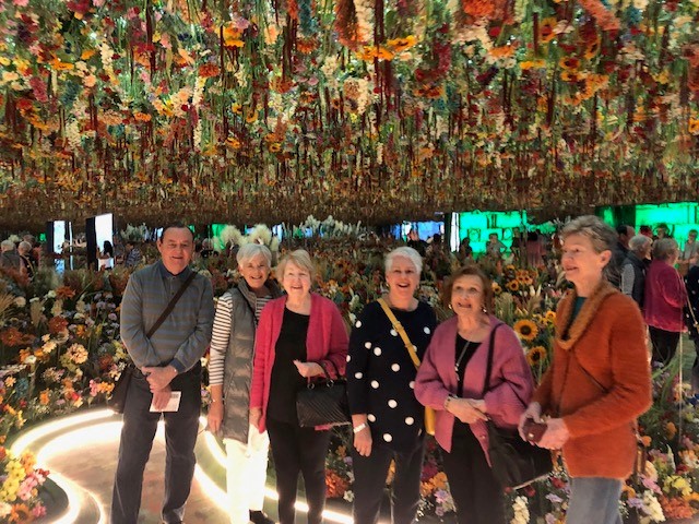 Samford Grove residents smiling under a sea of flowers at Monet in Paris exhibit.